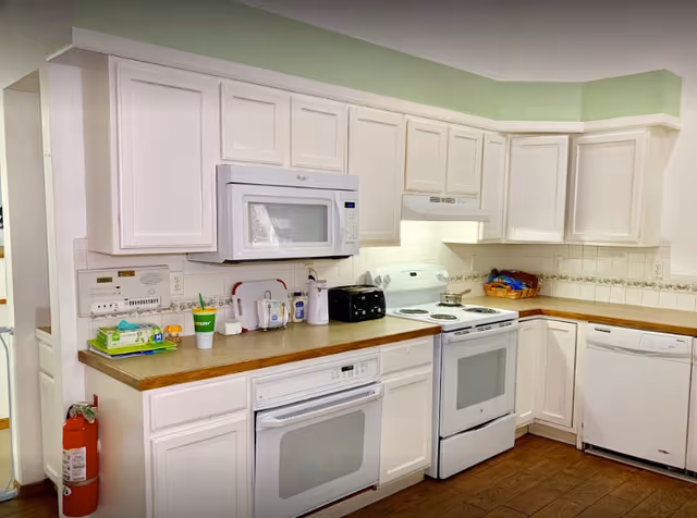 Bright kitchen with white cabinets and appliances including a microwave, oven, dishwasher, toaster, and countertop items.