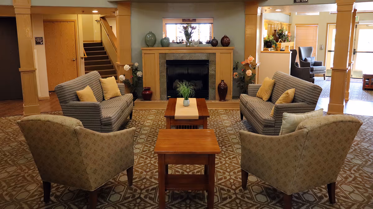 A cozy lounge area with sofas and a coffee table near a fireplace.