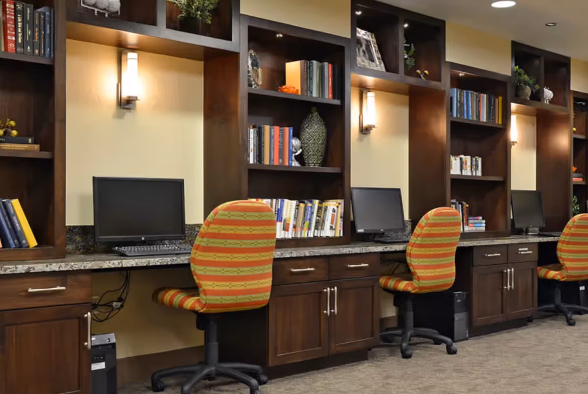 Row of computer workstations with striped swivel chairs set into dark wood built-in shelving and countertop.