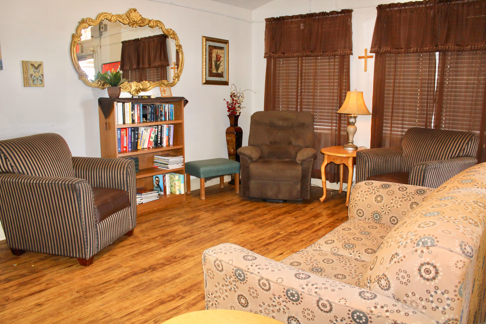 Cozy common living room with armchairs, a sofa, bookshelf, mirror and side table lamp.