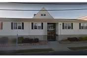 Front view of a single-story white senior care facility with a central entrance.