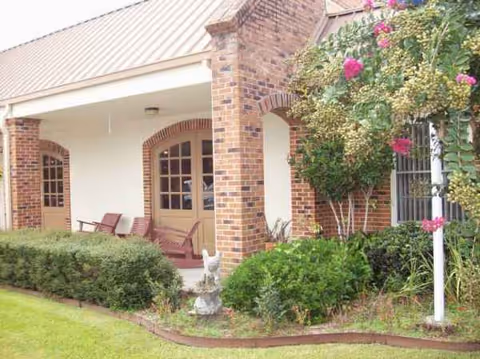 Brick nursing home entrance with arches, porch seating, and blooming rose bushes.