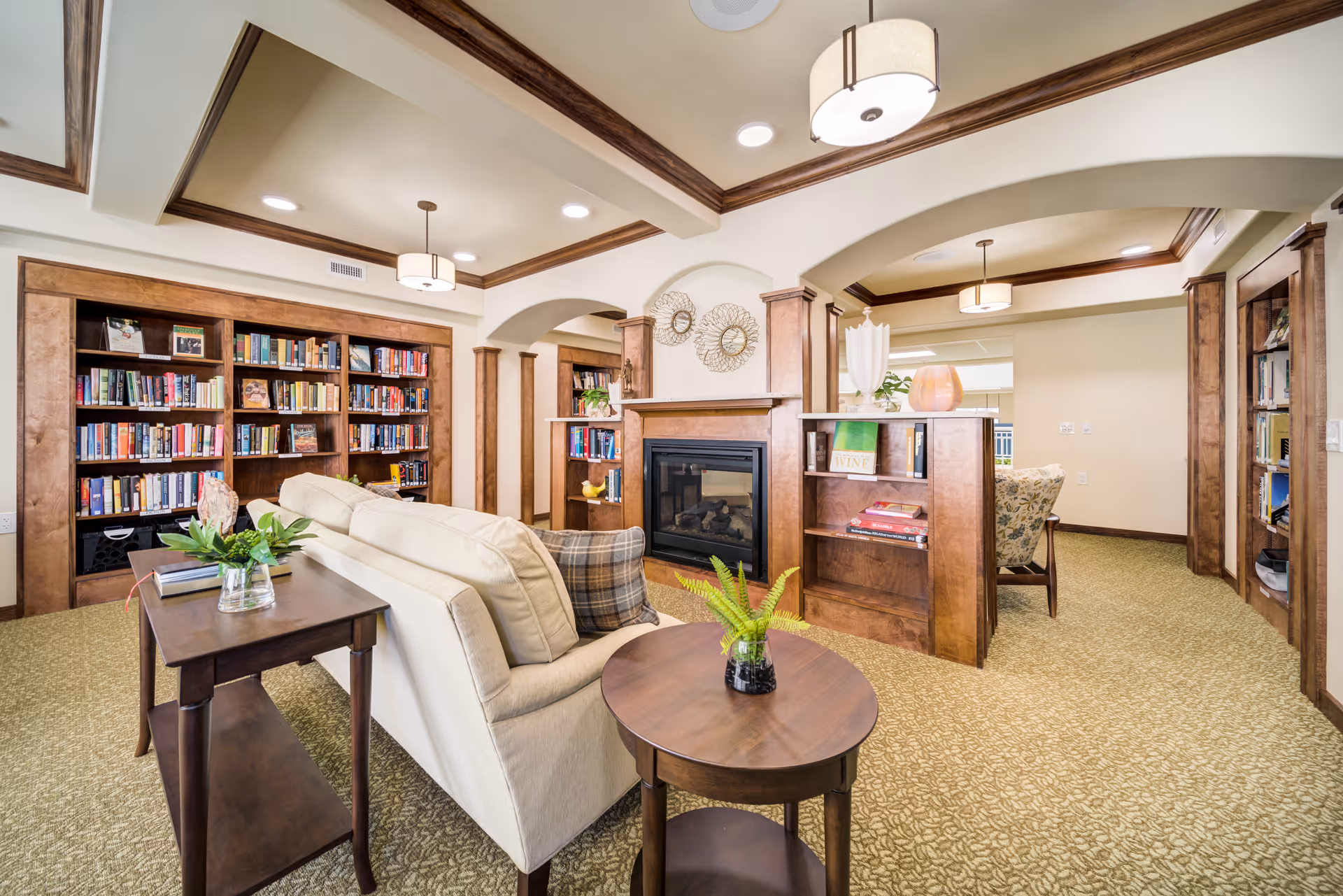 Cozy common living area with bookshelves, a fireplace, sofa and side tables.