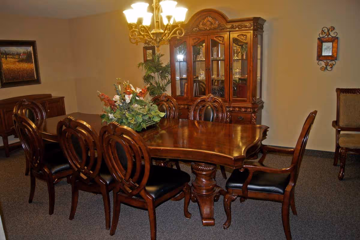 Formal dining room with a large polished wooden table, ornate chairs, a chandelier, and a glass-front china cabinet.