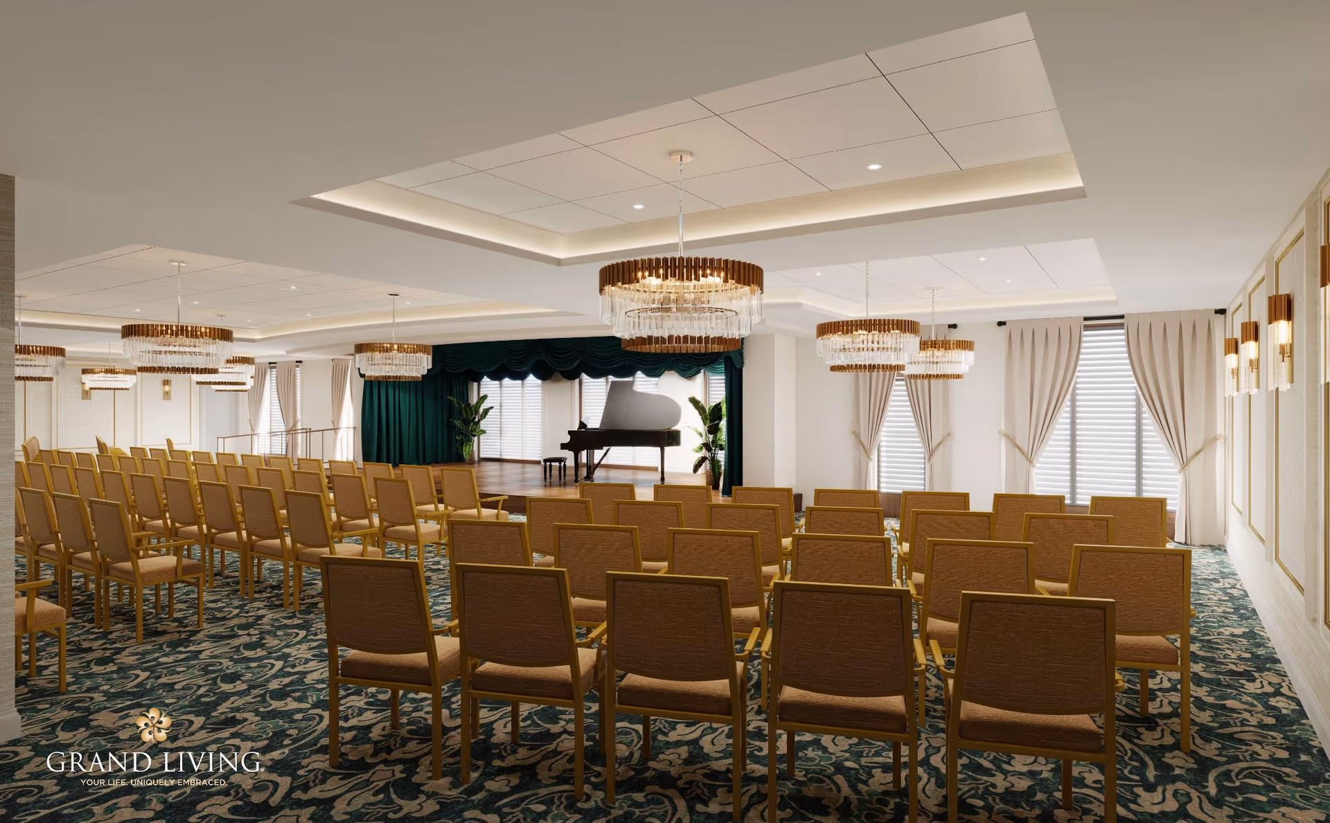 A spacious event room with rows of brown chairs facing a small stage with a black grand piano. The room features elegant chandeliers, patterned carpet, large windows with beige curtains, and white walls with decorative paneling.