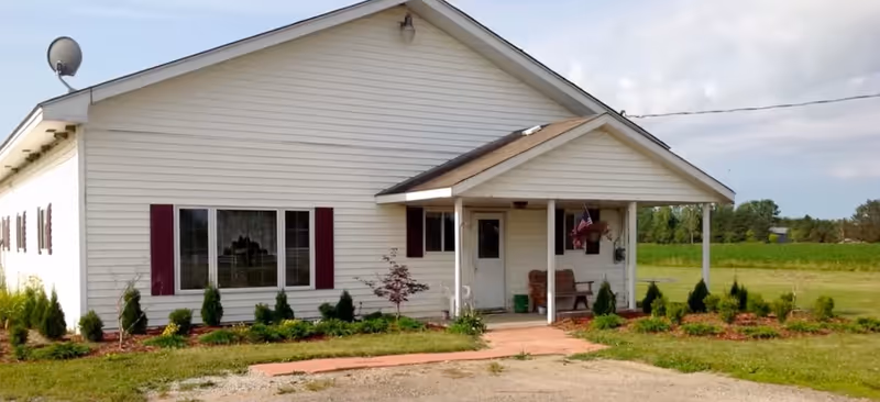 Single-story white facility building with a front porch and landscaped lawn.