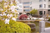 Exterior courtyard of a multi-story senior living building with landscaping and a pond.