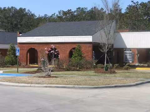 Exterior view of Heritage Healthcare facility with brick facade, arches, and landscaped front lawn.