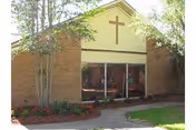 Front view of a brick senior care facility with a cross and glass entrance.