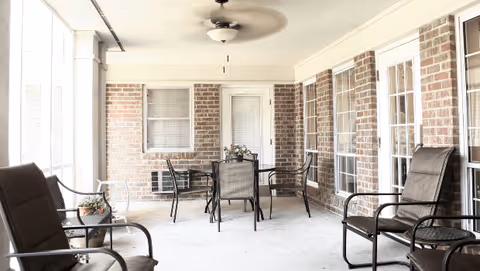 Covered brick patio with seating, a central table, and ceiling fans.