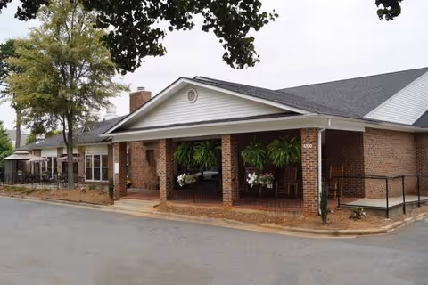 Exterior view of Queen City Assisted Living entrance with brick columns and hanging plants