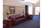 Interior living room at Millard County Care Center with red leather seating, lamps, and wall art.