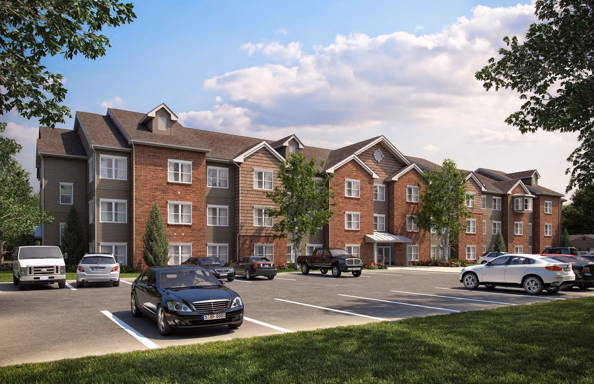 Exterior view of Ashley Grove Apartments, a three-story residential building with a combination of brick and siding facade. Several cars are parked in the parking lot in front of the building, and there are trees and grass surrounding the area under a partly cloudy sky.