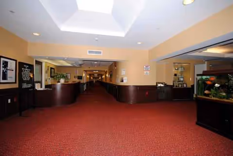 A long, well-lit interior hallway with reception desks and an aquarium at Massapequa Center.