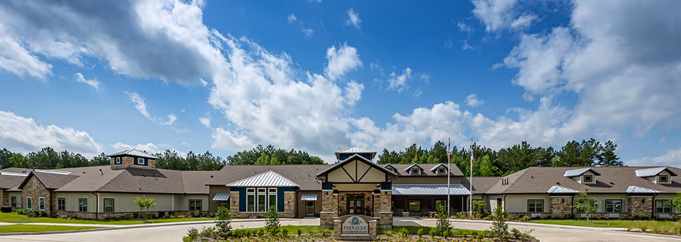 Pinnacle Senior Living building front with stone facade and clear blue sky.