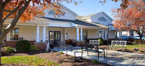 Brookdale Harrisonburg senior living facility entrance with columns, benches, and autumn trees.