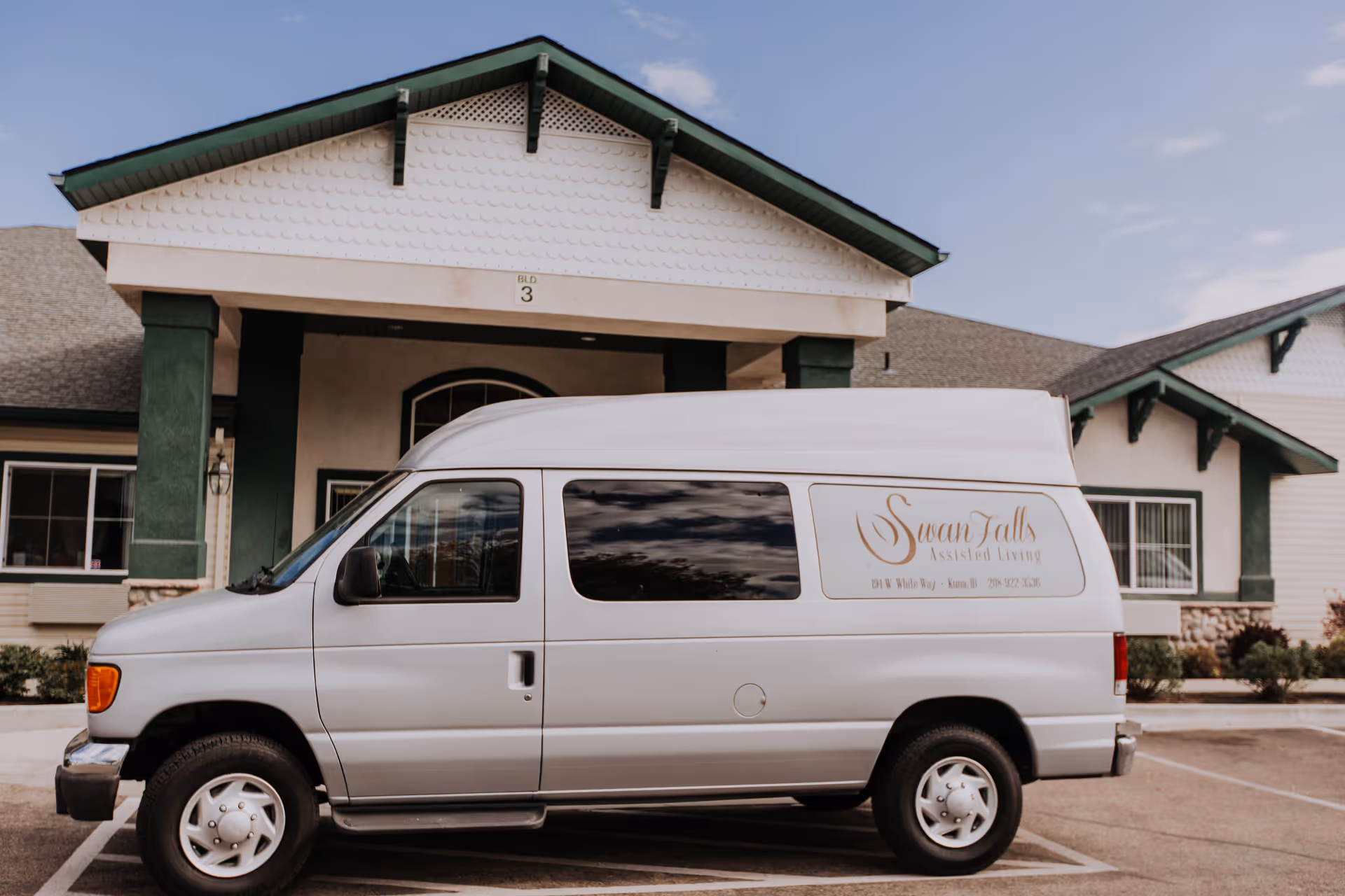 White Swan Falls Assisted Living shuttle van parked in front of the facility entrance.