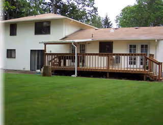 Exterior view of Bethel Home 4 showing a two-story building with a wooden deck and lawn.
