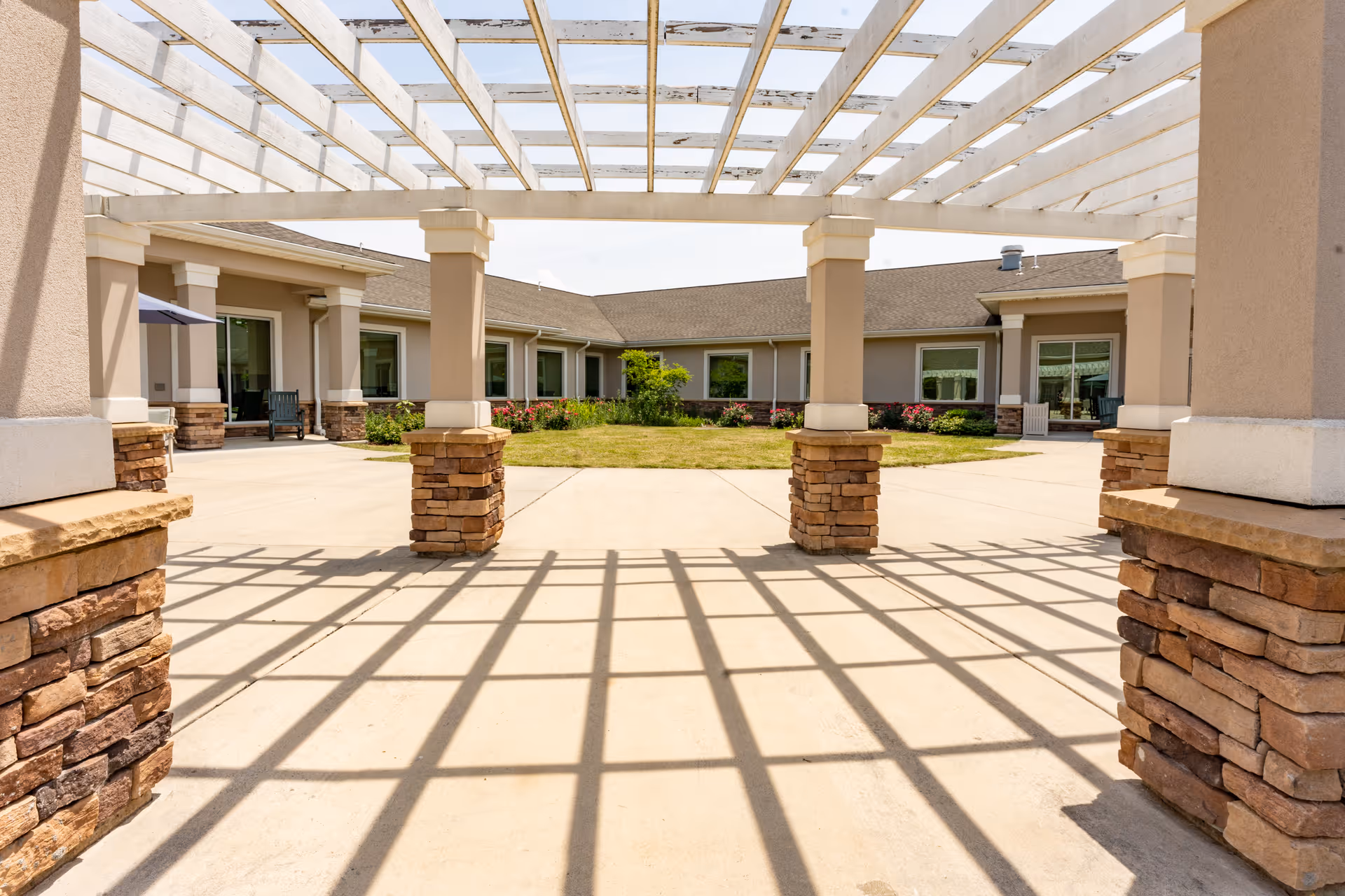 A view of a senior living facility's courtyard with a pergola and surrounding buildings.