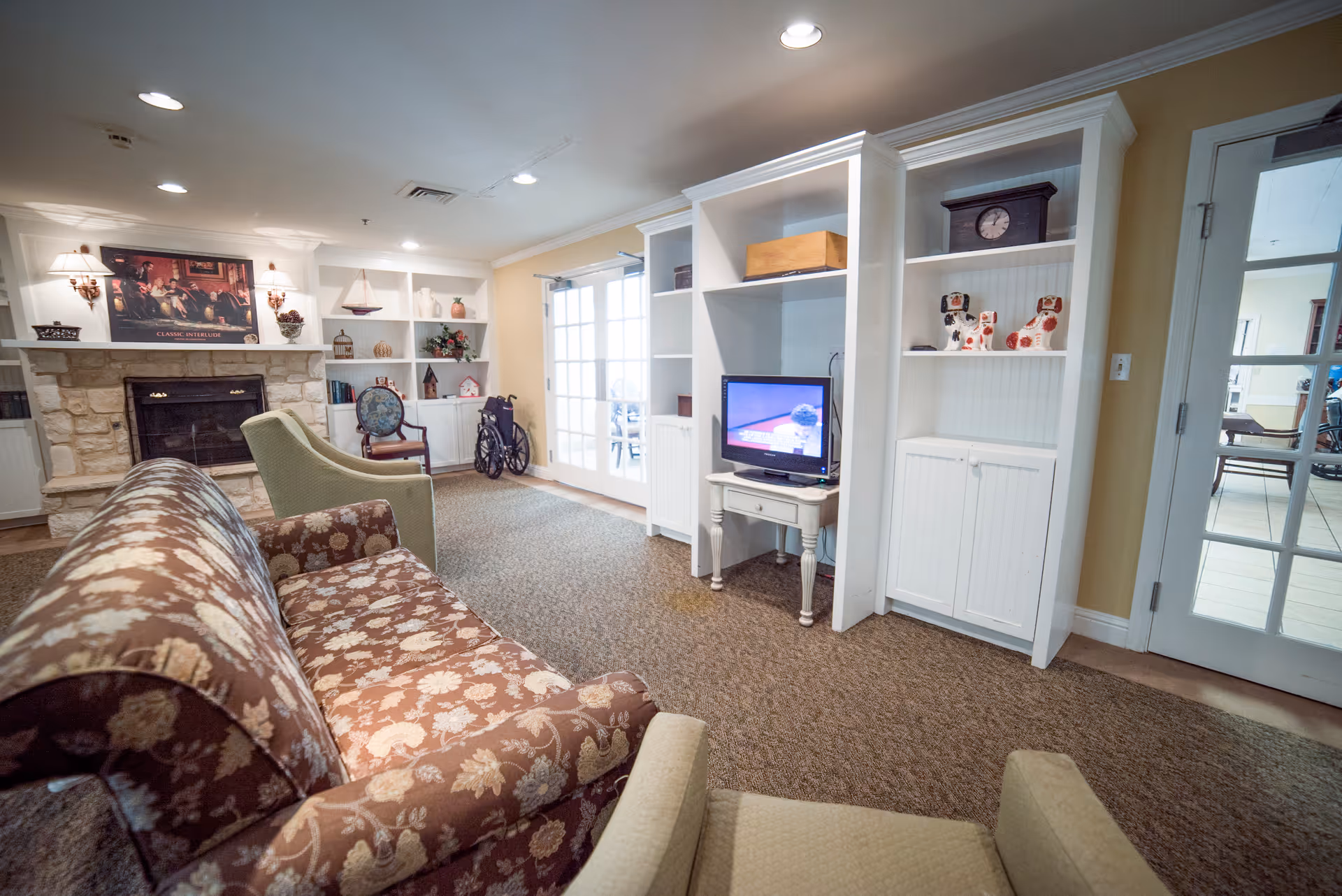 Cozy living room with patterned sofas, built-in white shelving, a small TV, and a stone fireplace.