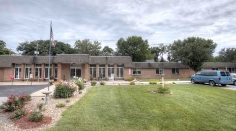 Front view of Wathena Healthcare and Rehabilitation Center with entrance, lawn, and parked van.