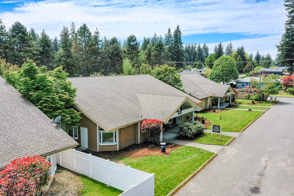 Aerial view of single-story cottage-style residential units with manicured lawns, landscaping, and a quiet street.