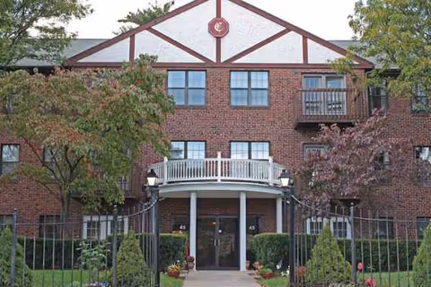 Front view of Canterbury senior living facility, brick building with entrance and surrounding trees.