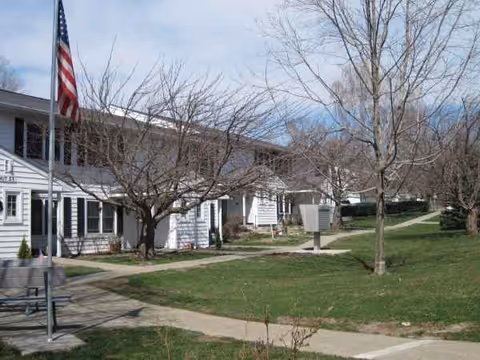 An exterior view of Chestnut Ridge Apartments with flagpoles, walkways, and bare trees.