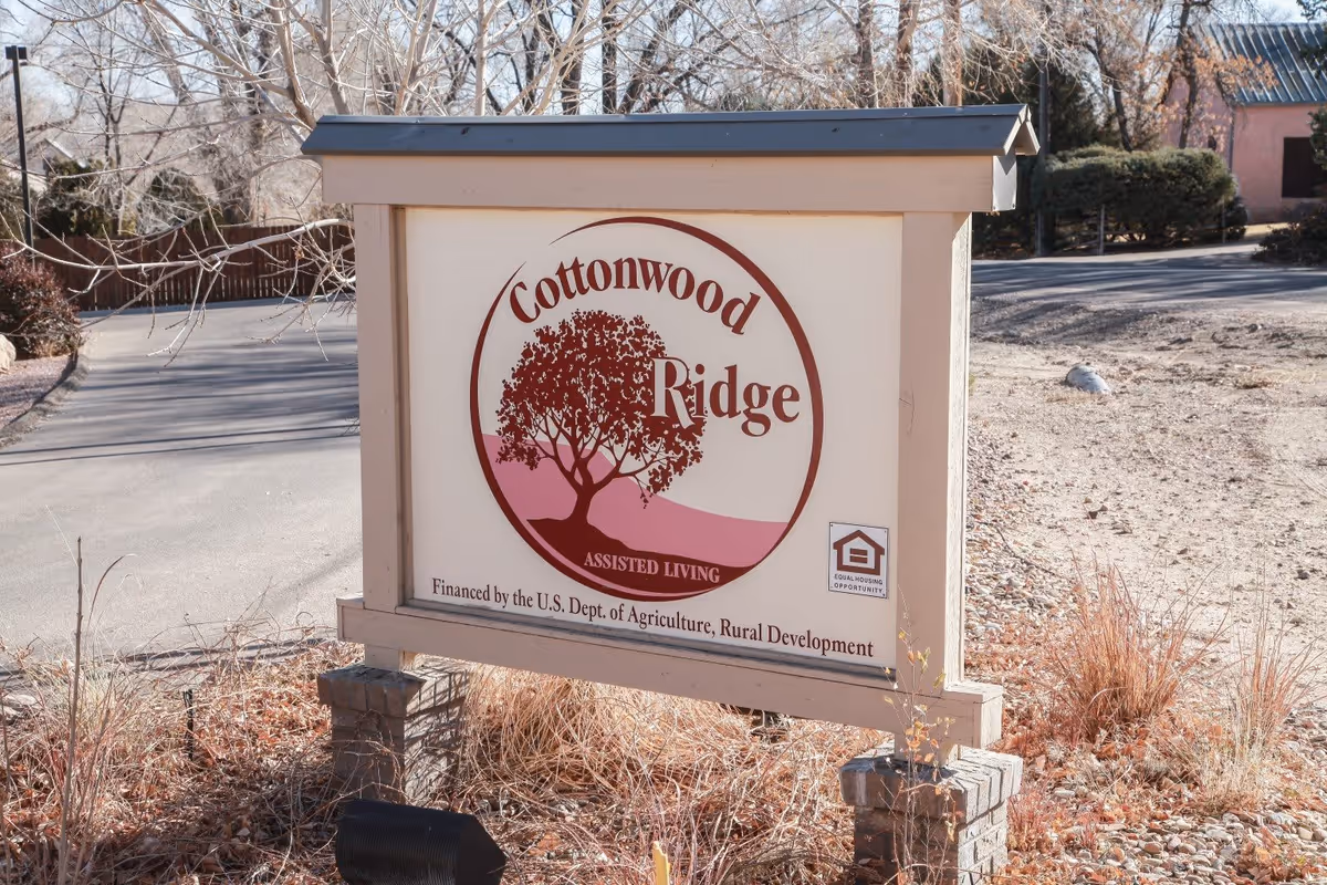 Outdoor sign for Cottonwood Ridge Assisted Living, featuring a tree logo and text indicating financing by the U.S. Dept. of Agriculture, Rural Development, with an Equal Housing Opportunity logo on the bottom right.