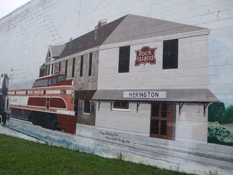 Mural of a building front featuring a red train and a Herington sign.