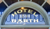 An arched window sign on a building facade reading 'HOTEL BARTH' with the number 1514 above.