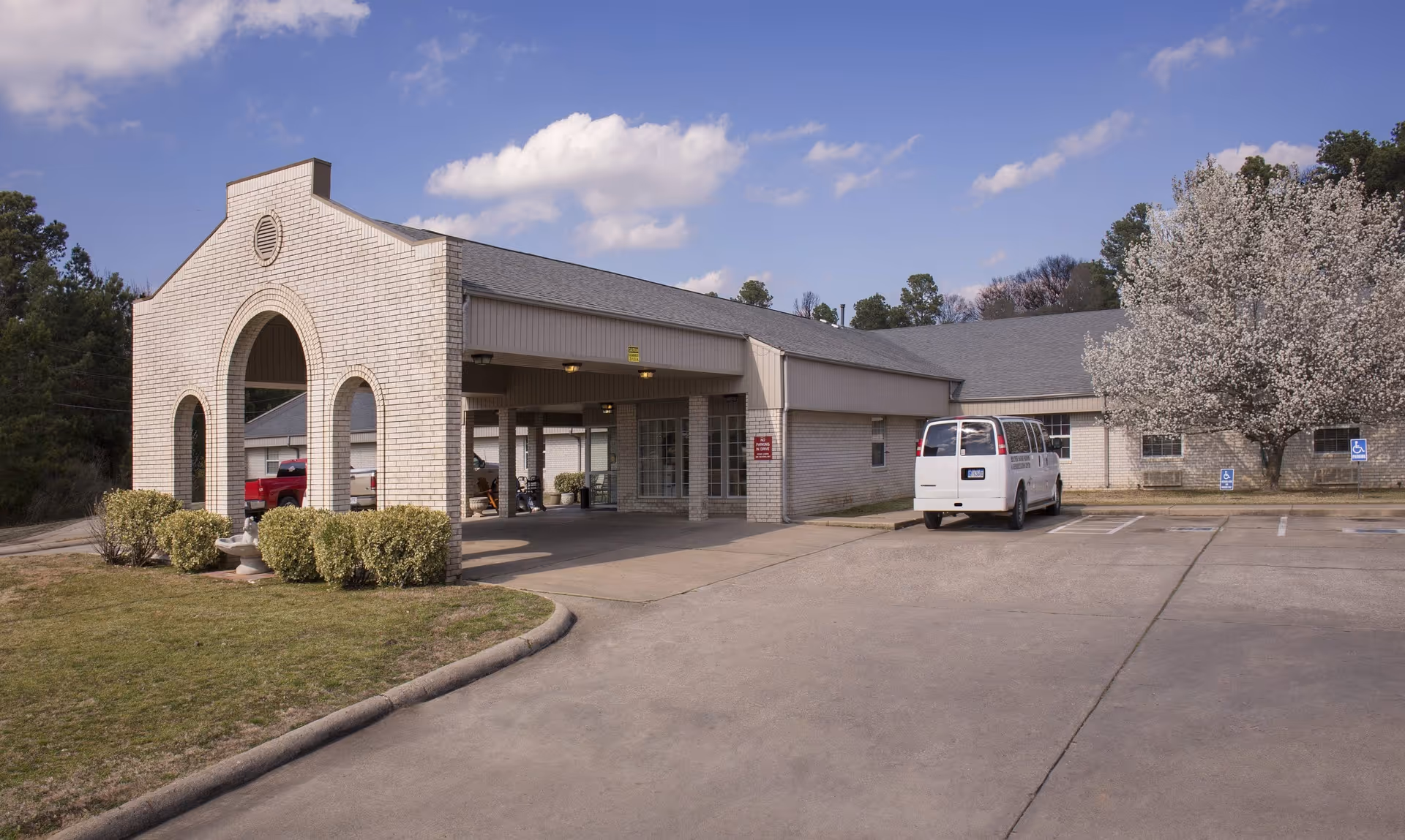 Exterior view of Heather Manor Rehabilitation with a flowering tree and parking area.