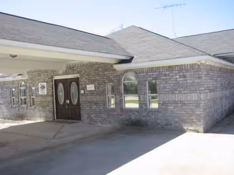 Brick building with a covered entrance and double doors, exterior view of facility.