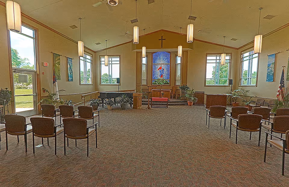 Chapel interior at Pleasant View Hearthstone AL with chairs, altar, cross, stained glass.