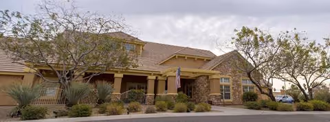 Exterior view of a single-story senior living facility with stone accents and desert landscaping.