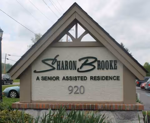 Front sign reading Sharon Brooke Assisted Living on a brick base