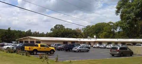 Exterior of Navasota Nursing and Rehabilitation, a single-story building with a long parking lot and cars.