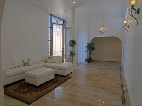 Bright lobby with white sectional sofa, plants, and arched doorway.