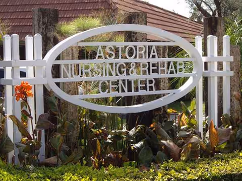 White gate and oval sign reading Astoria Nursing and Rehab Center at exterior entrance.