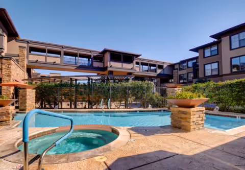 Outdoor courtyard featuring a swimming pool and circular hot tub surrounded by multi-story residential buildings.