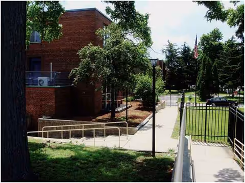 Exterior of Boulevard Manor showing brick building, walkway, railing, and trees.