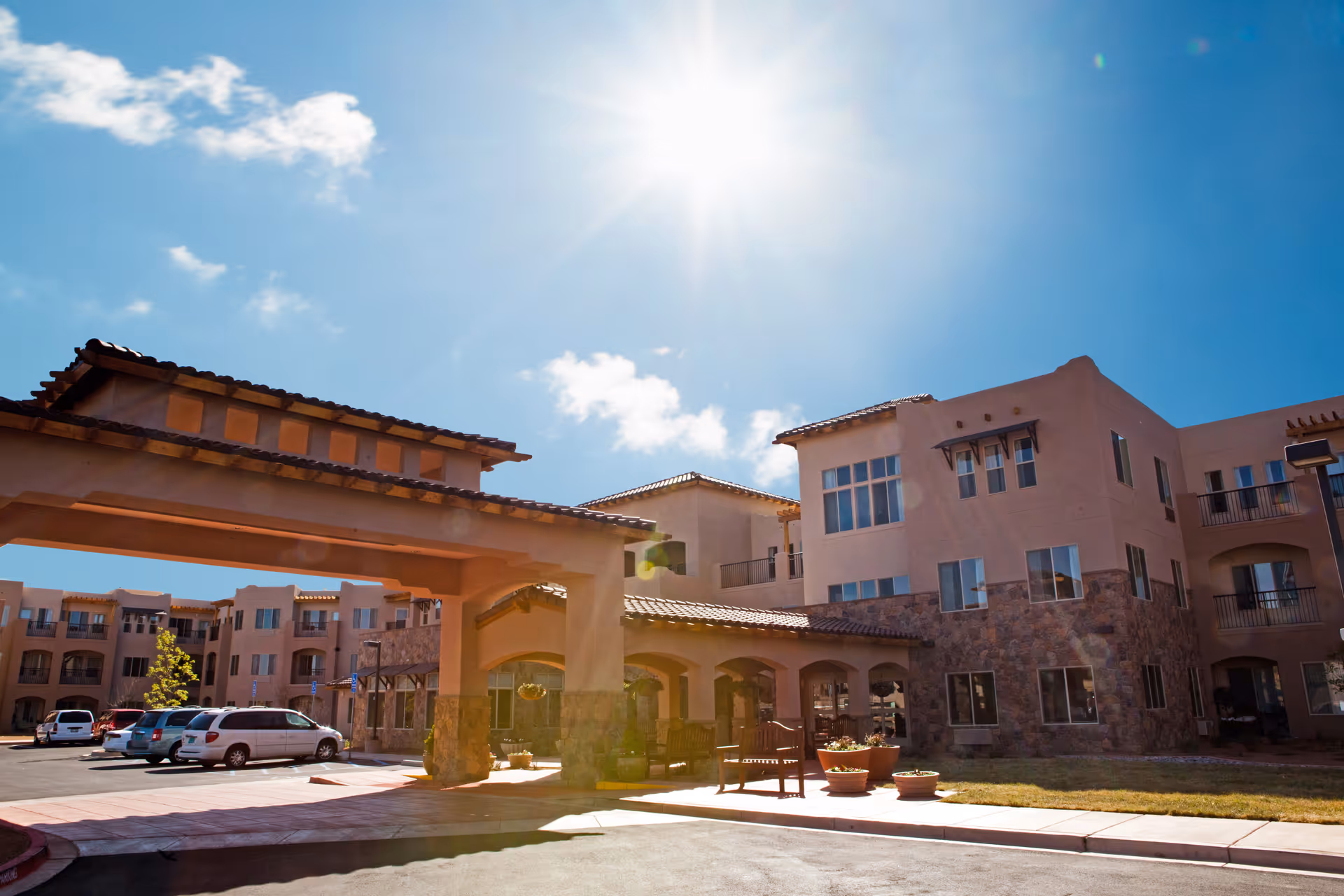Sunlit exterior view of a retirement living campus with a stucco building and welcoming entrance.