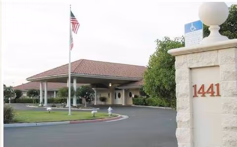 Front exterior of New Bethany Residential Care with entrance, driveway, and flagpole.