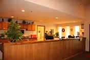 Reception desk in a warm, plant-filled lobby of a senior living facility.