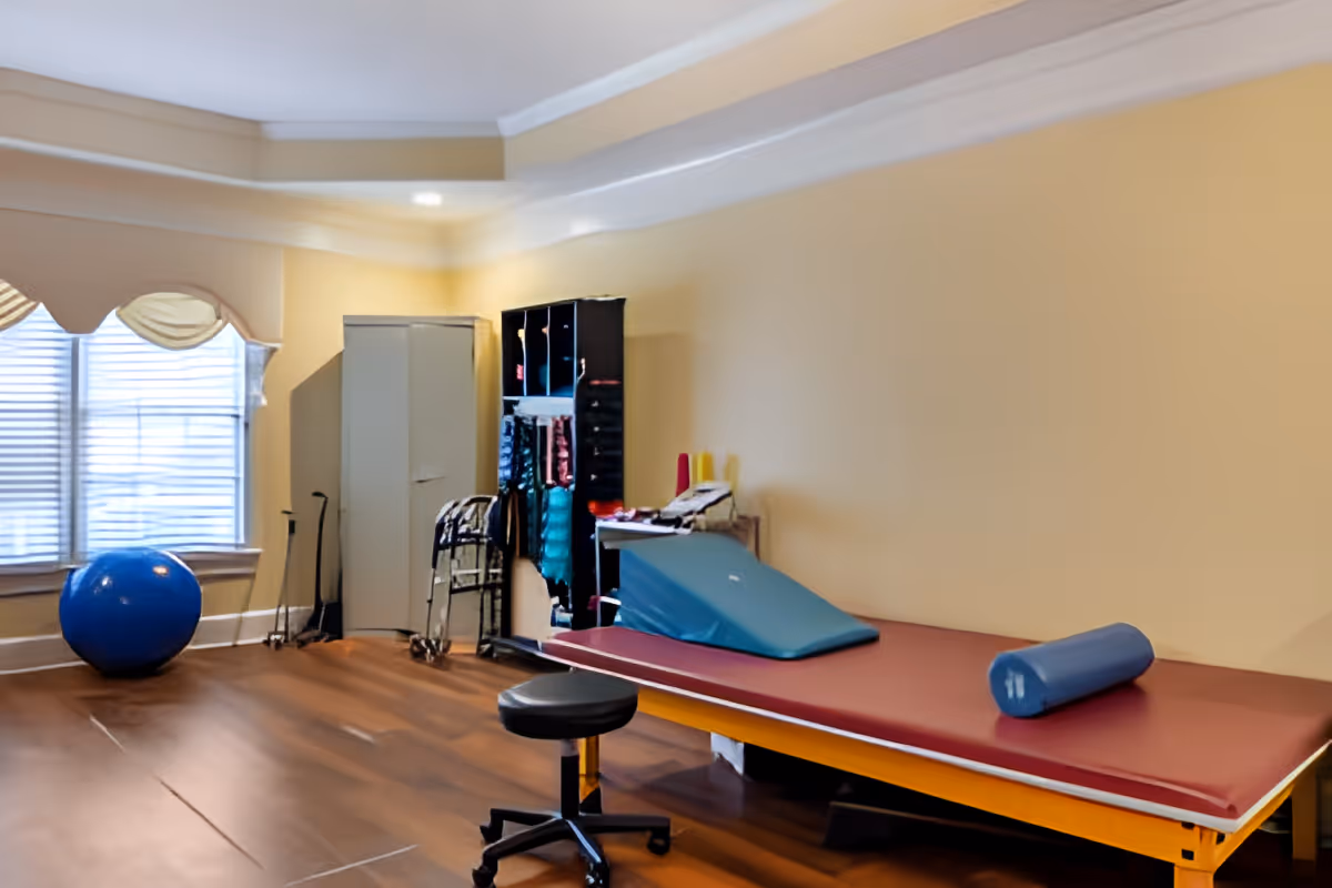 Physical therapy/exercise room with a treatment table, exercise ball, walkers, and storage cabinets.