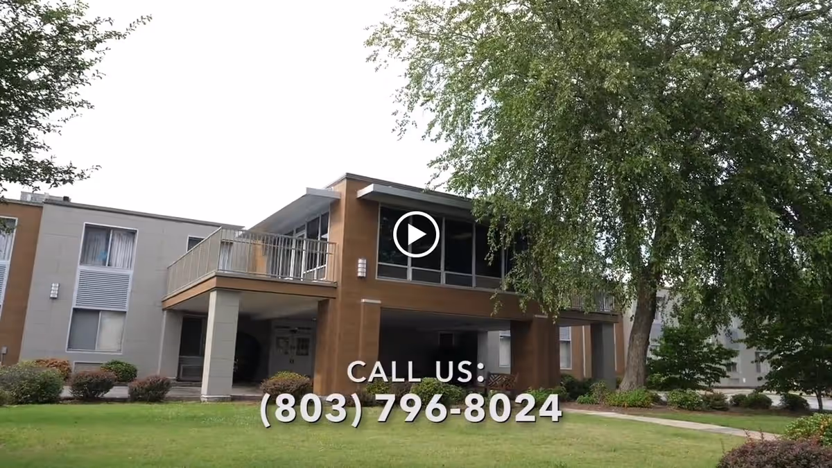 Front exterior of a two-story rehabilitation facility with balconies, lawn, and trees, overlaid with a phone number.
