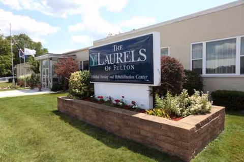 Exterior view of Laurels of Fulton facility with sign and landscaped front yard.