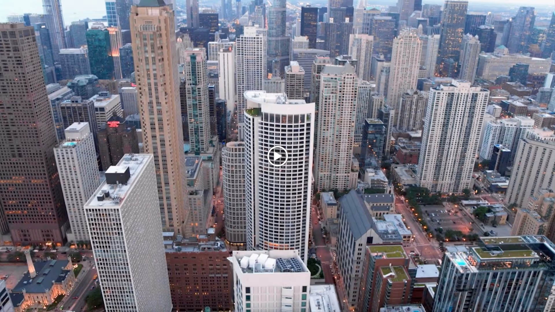 Aerial view of a dense downtown skyline with a prominent cylindrical high-rise in the center.