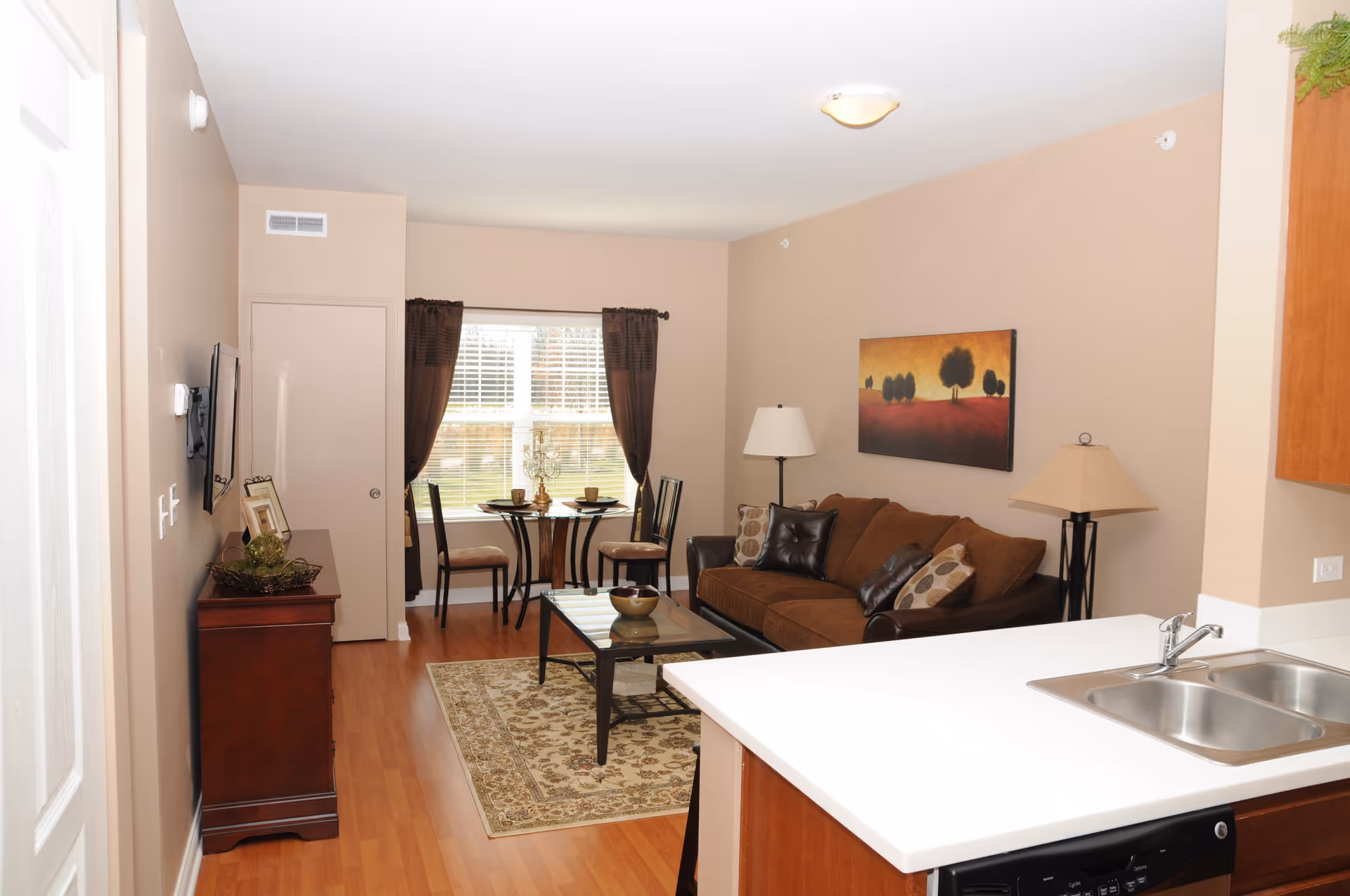 Open living area with sofa, coffee table, rug, dining table, and kitchen counter.