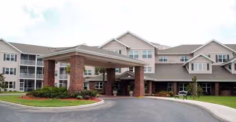 Exterior view of Venetian Gardens senior living facility with a covered entrance and driveway.